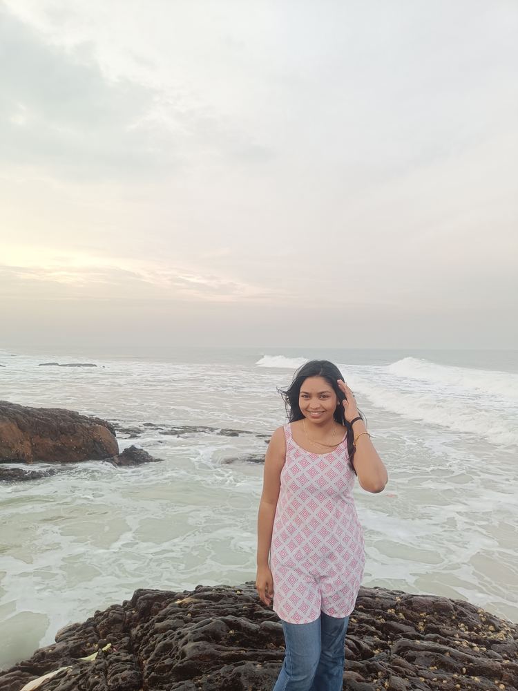 Shruti standing on the rocks with the waves behind her