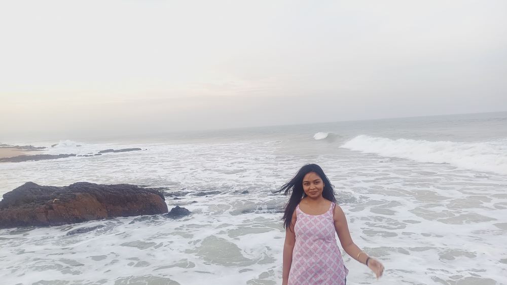 Shruti walking toward the camera near the shoreline