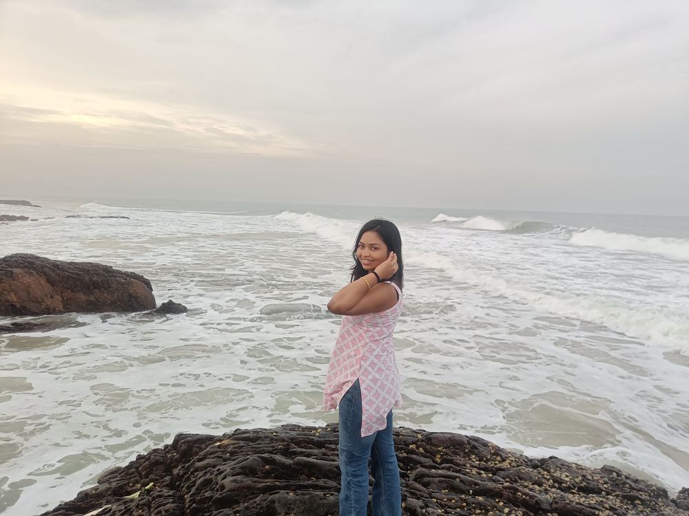 Shruti on the rocks by the sea, hair blowing in the wind