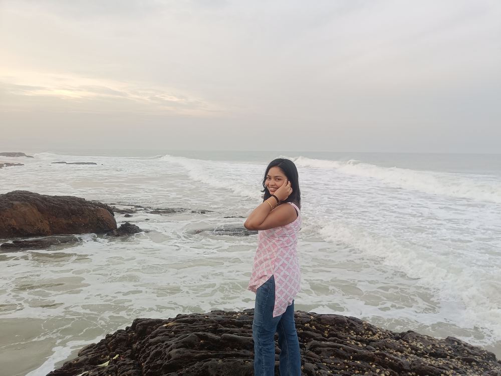 Shruti smiling by the ocean at golden hour