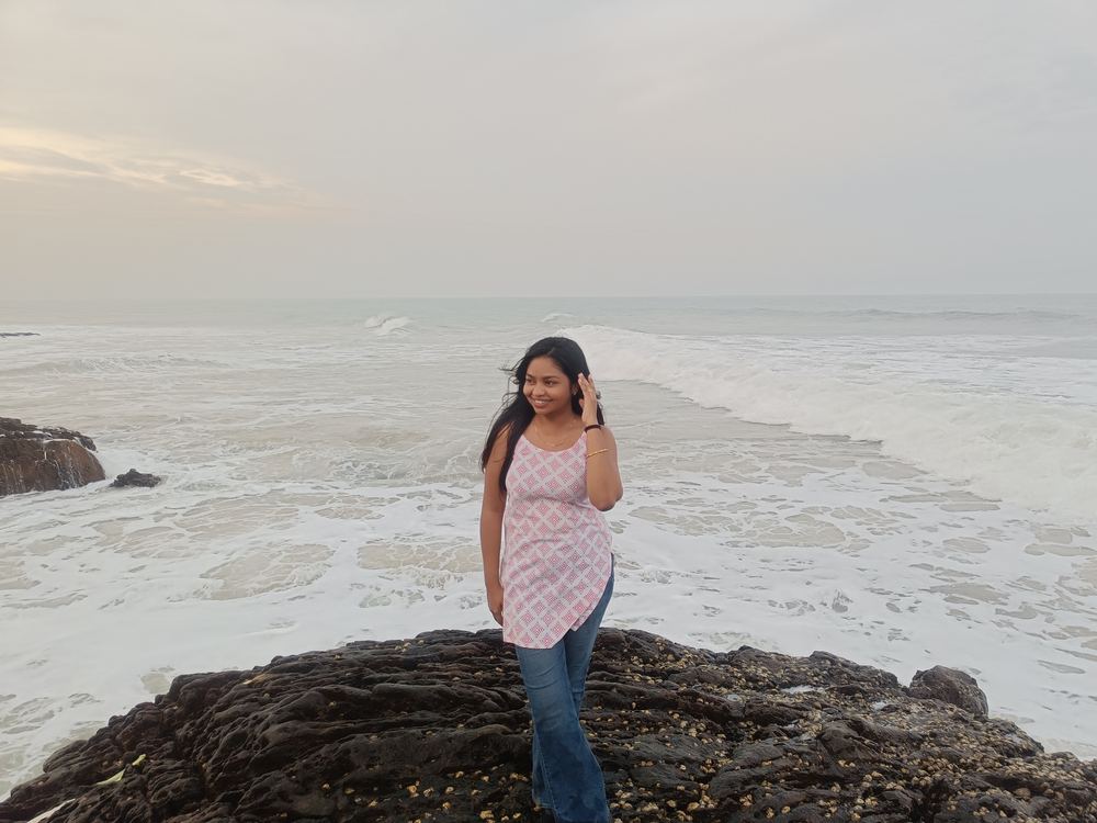Shruti walking barefoot across the rocks near the shore