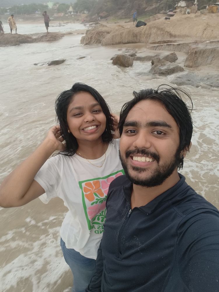 Shivam and Shruti soaked and smiling on a rainy beach