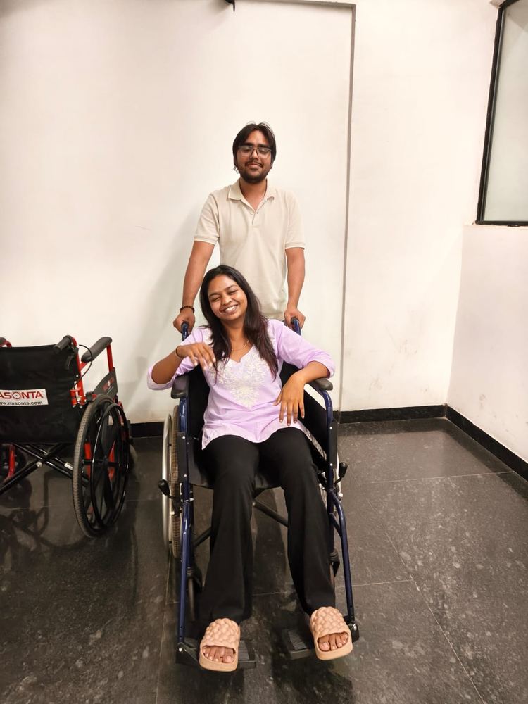 Shivam pushing Shruti around in a wheelchair, both laughing
